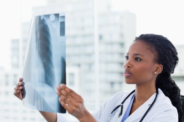 Female doctor looking at a set of X-rays clipart