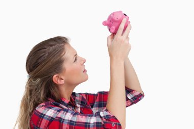 Woman looking inside a piggy bank clipart