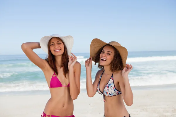 Happy young women standing on the beach side by side — Stock Photo, Image