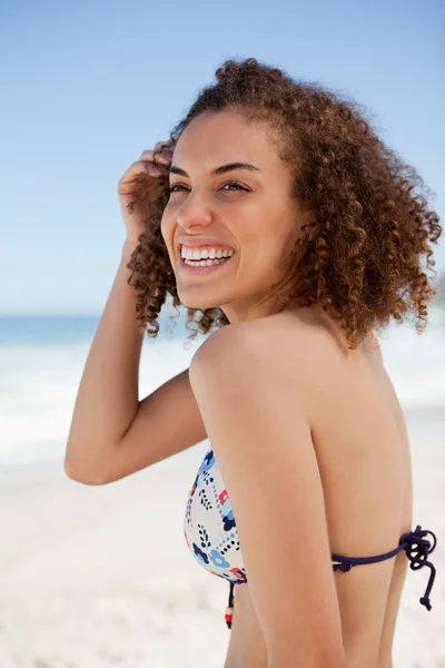 Mladá usměvavá žena dívá směrem k straně při umísťování její h — Stock fotografie
