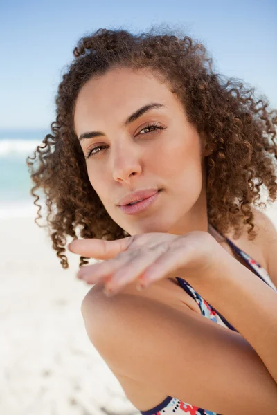 Young woman sending an air kiss while blowing on her hand — Stock Photo, Image