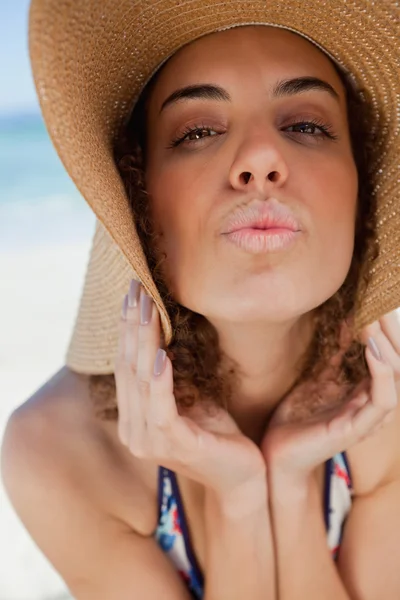 Jovem mulher usando um chapéu de palha enquanto puckering seus lábios — Fotografia de Stock