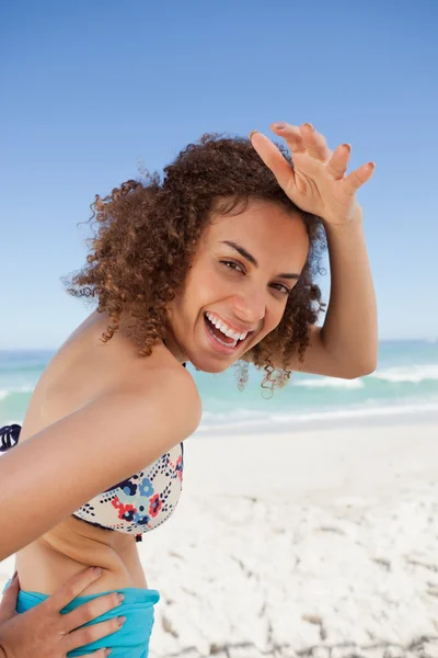 Junge lächelnde Frau legt ihre Hand auf ihre Stirn, um sie anzusehen — Stockfoto