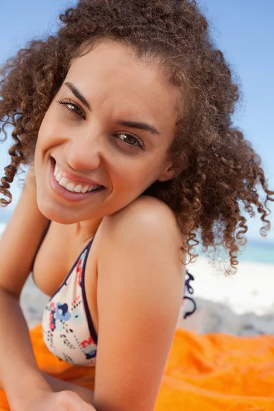 Молода усміхнена жінка лежить на пляжному рушнику, дивлячись на — стокове фото