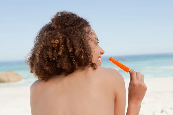 Smiling attractive woman holding an orange ice lolly — Stock Photo, Image