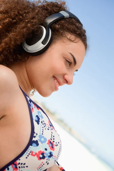 Schöne junge Frau im Bikini hört Musik am Strand — Stockfoto