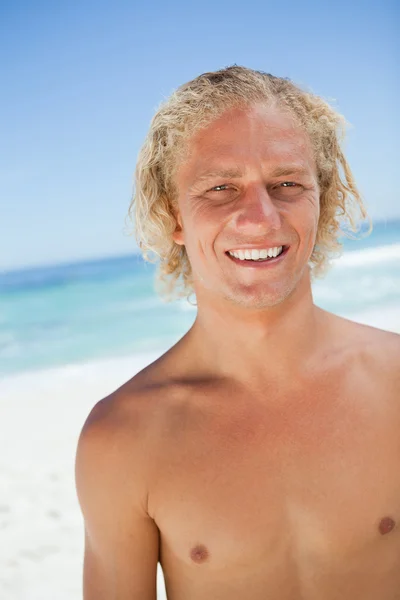 Usměvavá blondýnka muž při pohledu na fotoaparát stoje na b — Stock fotografie