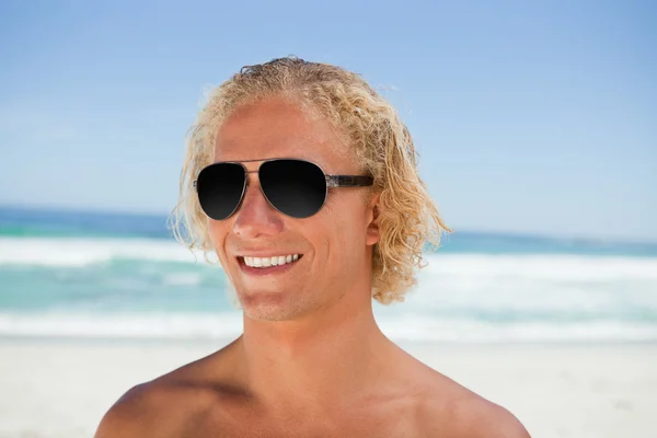 Gülümseyen adam sahilde duran güneş gözlüğü takıyor — Stok fotoğraf