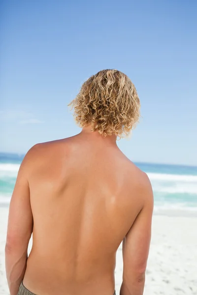 Visão traseira de um jovem loiro olhando para o oceano — Fotografia de Stock