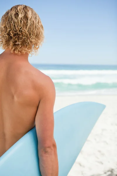 Junger blonder Mann mit seinem blauen Surfbrett — Stockfoto