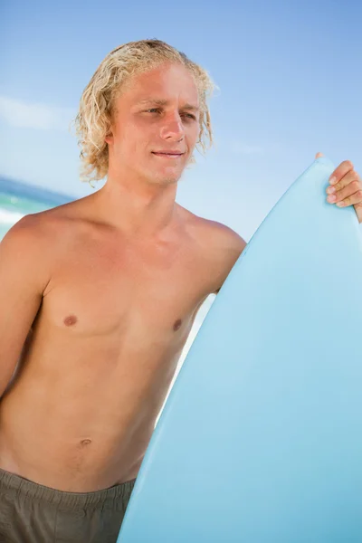 Młody mężczyzna atrakcyjny, trzymając jego wznosi deska surfingowa przed t — Zdjęcie stockowe