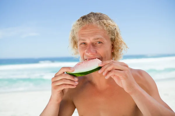 年轻男子在大海面前吃了一块西瓜 — 图库照片