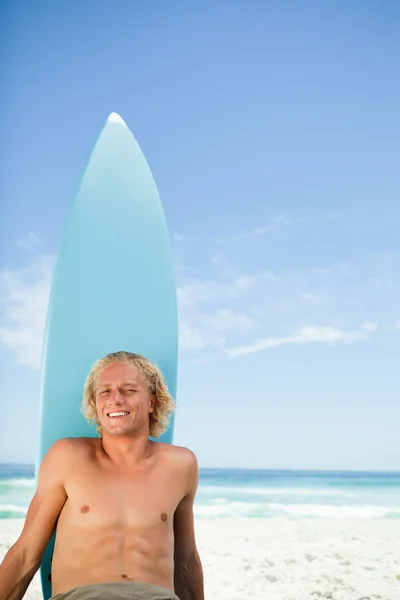 微笑着金发碧眼的人和他的冲浪板 ne 在沙滩上晒日光浴 — 图库照片