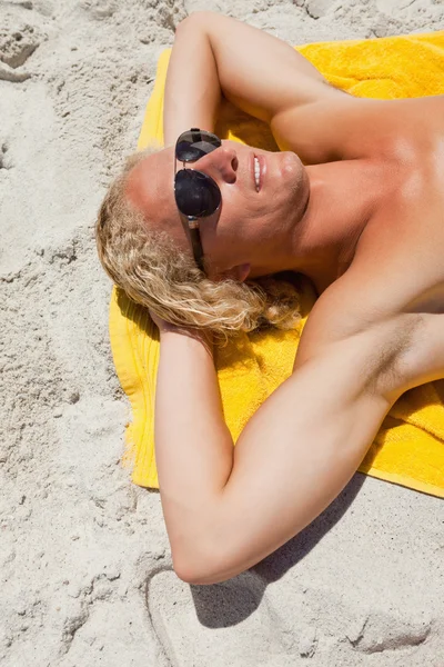 Giovane uomo biondo che indossa occhiali da sole mentre sdraiato sul suo giallo essere — Foto Stock