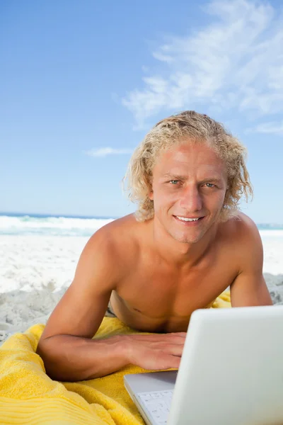 Χαμογελώντας ξανθιά άνθρωπος κοιτάζοντας την κάμερα κατά τη χρήση του φορητού υπολογιστή — Φωτογραφία Αρχείου