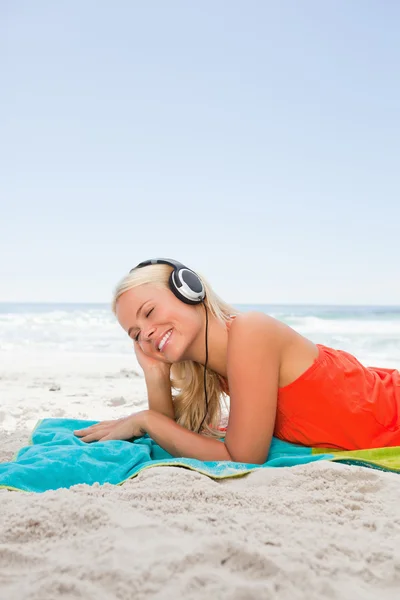 Unga blonda kvinnan ligga ner medan du lyssnar på musik — Stockfoto