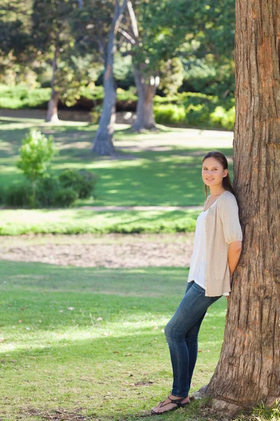 Mujer en el campo apoyada contra un árbol — Foto de Stock