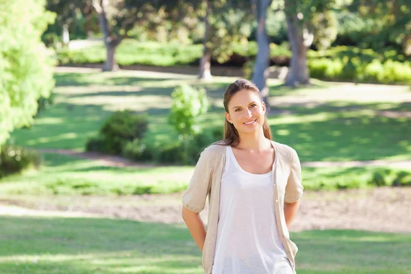 Usmívající se žena stojící v parku — Stock fotografie