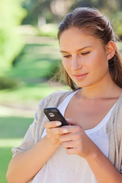 Nahaufnahme einer Frau, die im Park eine SMS schreibt — Stockfoto