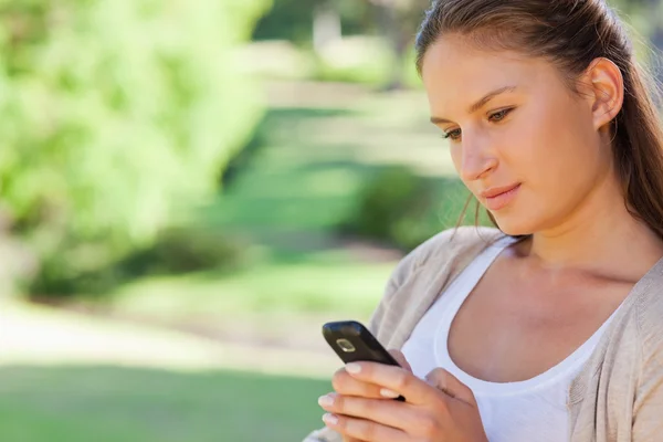 Närbild på kvinna läser en textmeddelande i parken — Stockfoto