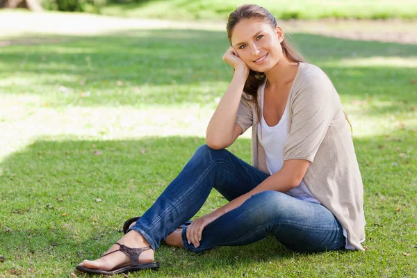 草の上に座っている女性の笑みを浮かべてください。 — ストック写真