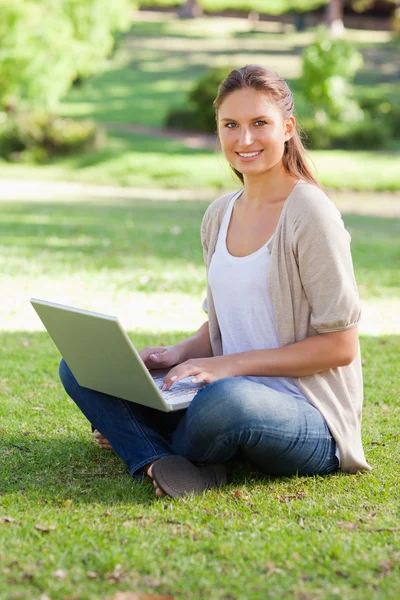 웃는 여자는 공원에서 그녀의 노트북에 — 스톡 사진