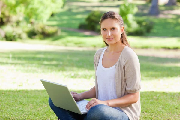 Donna con il suo computer portatile seduto sull'erba — Foto Stock