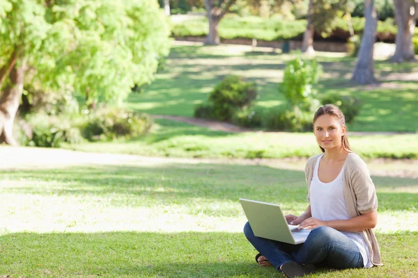 她坐在公园的笔记本电脑的女人 — 图库照片