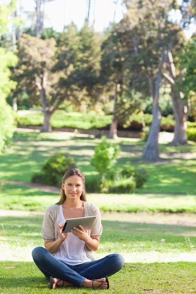 彼女のタブレットを使用しながら、芝生の上に座っている女性 — ストック写真