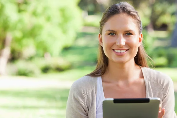Улыбающаяся женщина сидит на газоне с планшетным компьютером — стоковое фото