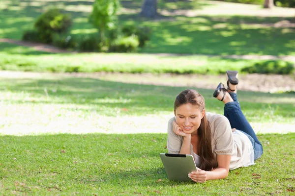 Vrouw opleggen op het gazon met een tablet pc — Stockfoto