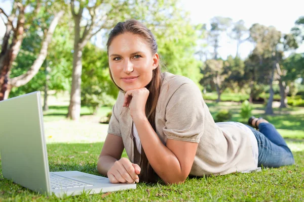 Frau liegt mit ihrem Notizbuch auf dem Rasen — Stockfoto