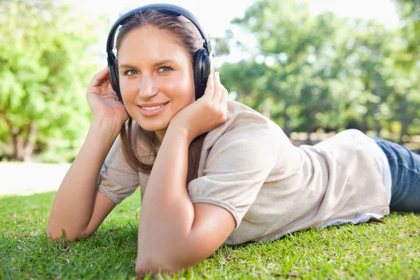Женщина слушает музыку на газоне — стоковое фото