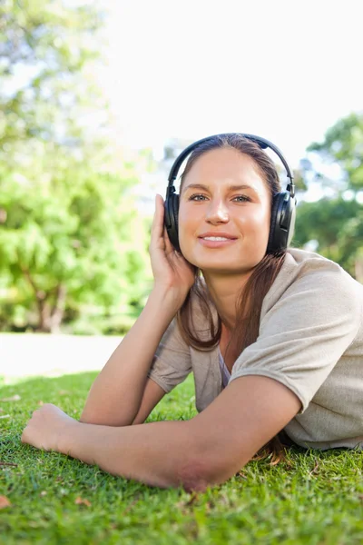 Woman with headphones lying on the grass — Stock Photo, Image