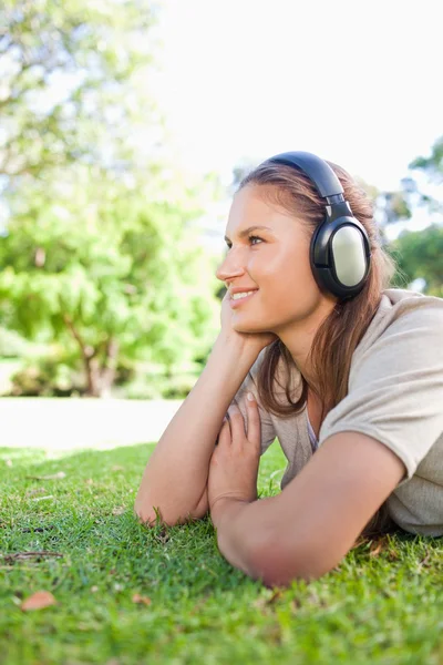 Вид сбоку женщины, слушающей музыку на лавке — стоковое фото