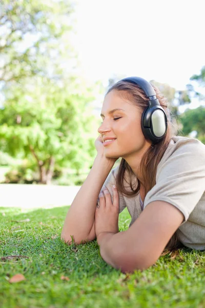 女人享受音乐在草坪上的侧视图 — 图库照片