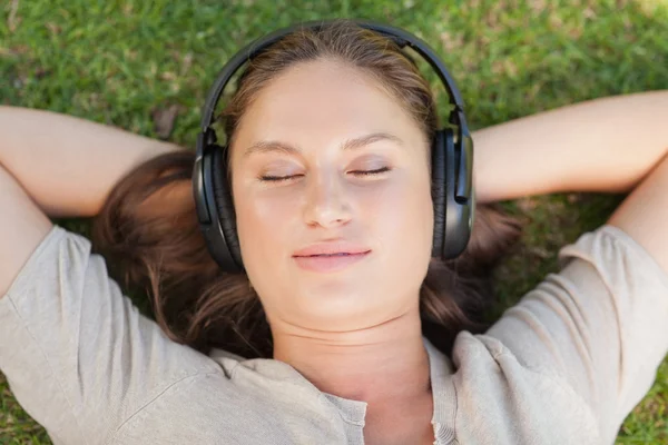 Mujer relajada tumbada en el césped mientras escucha música —  Fotos de Stock