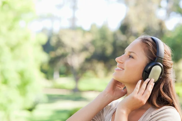 Side view of a woman in the park enjoying music — Stock Photo, Image