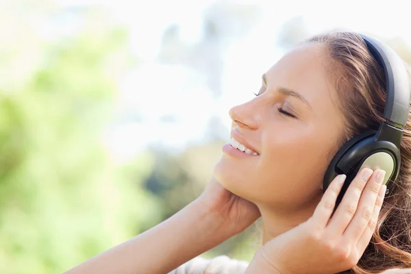 Side view of a woman enjoying music in the park — Stock Photo, Image