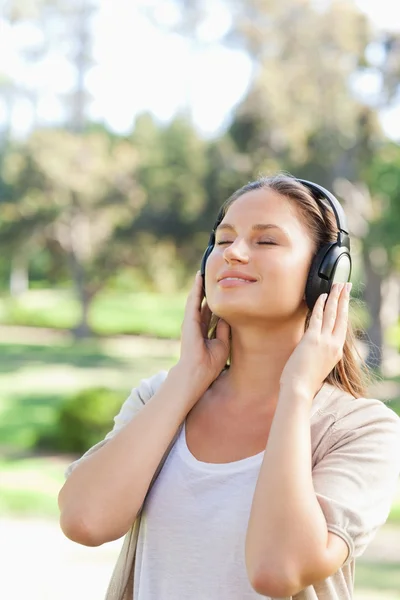 Vrouw met hoofdtelefoon genieten van muziek in het park — Stockfoto