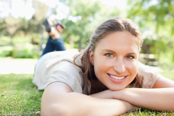 Usmívající se žena ležící na trávníku — Stock fotografie