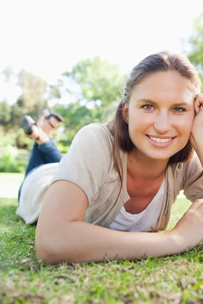 Lachende vrouw opleggen op het gras — Stockfoto