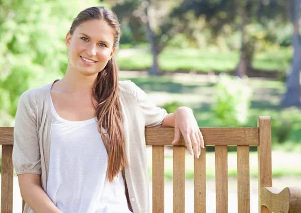 公園のベンチに座っている女性の笑みを浮かべてください。 — ストック写真