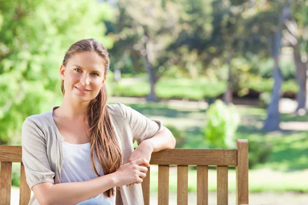 Relaxed woman sitting on a park bench — Stock Photo, Image