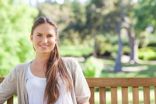 Smiling woman relaxing on a park bench — Stock Photo, Image