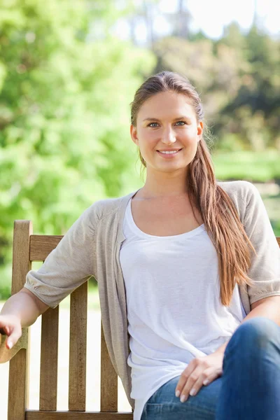 Smiling woman enjoying her day on a park bench — Stock Photo, Image