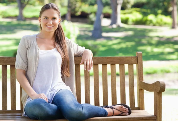 Kvinnan sitter på en bänk i parken — Stockfoto