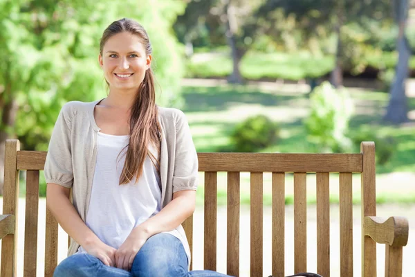 Gülümseyen kadın parkta bir bankta rahatlatıcı — Stok fotoğraf