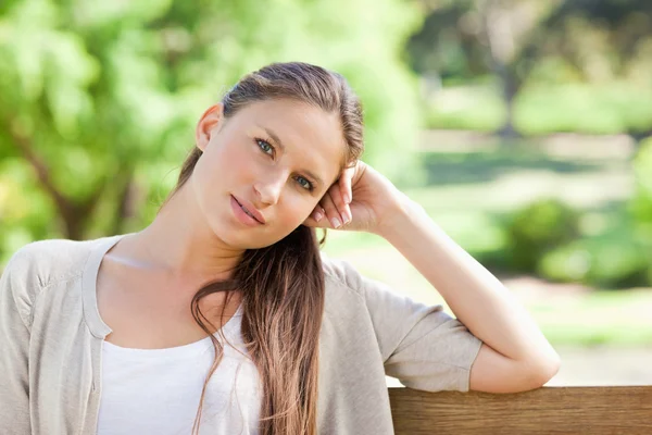 Thoughtful woman sitting on a park bench — Stock Photo, Image