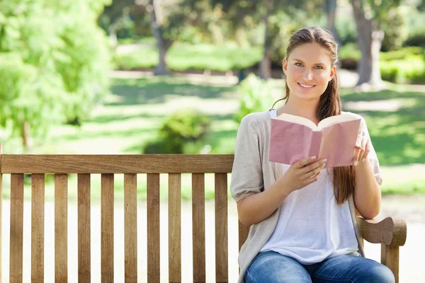 Bir kitap bir parkta bankta oturan kadın — Stok fotoğraf